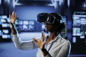 Trained technician in data center uses virtual reality to prevent system overload. Experienced VR headset user in server room ensuring enough network bandwidth for smooth operations photo