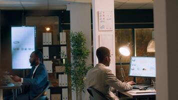 Supervisor teaching newcomer how to properly solve project tasks during inductment period in modern office. Manager working nightshift helping employee during company onboarding process photo
