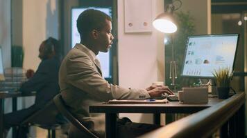 African american employee pissed about noisy coworker listening to music and pretending to beat drums in office. Businessman frustrated with overzealous colleague banging desk photo