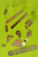 a pile of metal clips and screws on a green surface photo