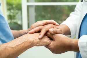 Caregiver holding hands Asian elderly woman patient with love, care, encourage and empathy at nursing hospital, healthy strong medical concept. photo