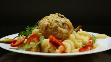 cooked pasta with meatballs, peppers and herbs with spices in a plate video