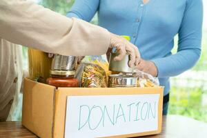 voluntarios poniendo varios alimentos secos en cajas de donación para ayudar a las personas. foto