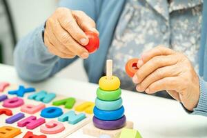 Alzheimer disease AD, Asian elderly woman patient suffering from dementia learn practical motor skills rehabilitation. photo