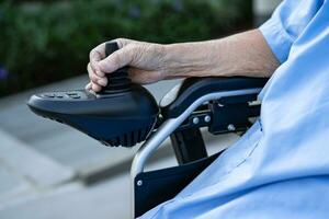 Asian senior woman patient on electric wheelchair with remote control at hospital, healthy strong medical concept. photo