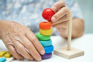 Alzheimer disease AD, Asian elderly woman patient suffering from dementia learn practical motor skills rehabilitation. photo