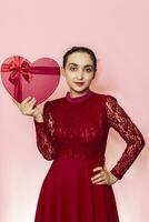 Portrait of attractive Hispanic woman holding giftbox. Valentines day gifts. Beautiful middle-eastern girl receives heart-shaped present box. Love day, anniversary, birthday celebration photo