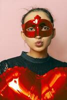 Woman wearing masquerade mask and holding heart shaped air ballon. Valentines Day, Birthday, Anniversary, Festive, Ball celebration concepts photo