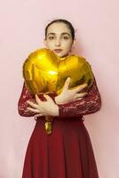 Attractive iranian woman hold golden heart shaped air balloon. Celebrating Valentines day. Beautiful Happy Young middle-eastern girl. Holiday party, Love day, anniversary, birthday celebration photo