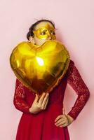 Woman wearing masquerade mask and holding heart shaped air ballon. Valentines Day, Birthday, Anniversary, Festive, Ball celebration concepts photo