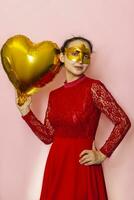 Woman wearing masquerade mask and holding heart shaped air ballon. Valentines Day, Birthday, Anniversary, Festive, Ball celebration concepts photo