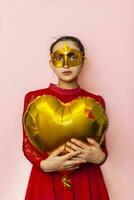 Woman wearing masquerade mask and holding heart shaped air ballon. Valentines Day, Birthday, Anniversary, Festive, Ball celebration concepts photo