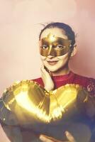 Woman wearing masquerade mask and holding heart shaped air ballon. Valentines Day, Birthday, Anniversary, Festive, Ball celebration concepts photo