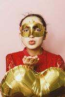 Woman wearing masquerade mask and holding heart shaped air ballon. Valentines Day, Birthday, Anniversary, Festive, Ball celebration concepts photo