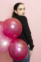 Young pretty woman in casual clothing holding festive air balloons. Portrait of happy 20s middle-eastern female celebrating valentines day, birthday, party photo