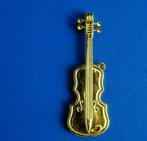 a gold tone violin charm on a blue background photo