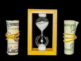 two five dollar bills and an hourglass are next to each other photo