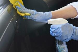 Car disinfecting service. Woman disinfecting inside car door handle photo