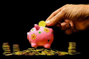 a hand putting coins into a piggy bank photo