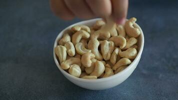 child hand pick cashew nuts in a small bowl on black color background video