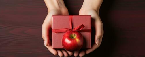 Female hands holding a gift box with a red bow on a red background photo