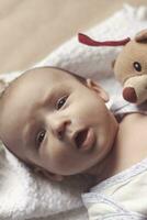 2 month baby boy lying. Close-up of adorable cute newborn baby boy of two months on soft textile. Lovely child playing with plush toy photo