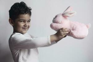 5 years adorable little kid boy playing with plush rabbit bunny toy photo