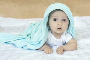 6-8-month-old baby boy lying playfully in bed. Charming 6-7 month little baby in white bodysuit. Baby boy in white bedding. Copy space photo