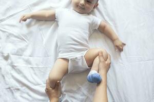 Baby massage. Mom doing gymnastics with kid. Mommy massaging cute baby boy. Moving baby's legs to help relieve constipation. Young mother doing exercises and movements to stimulate baby's bowels. photo