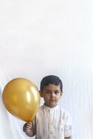 retrato de 5-6 años antiguo chico con globo. adorable medio oriental niño participación un dorado globo. celebrando, fiesta concepto. foto