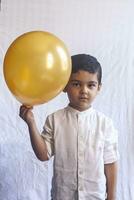 Portrait of 5-6 years old boy with balloon. Adorable middle eastern kid holding a golden balloon. Celebrating, holiday concept. photo