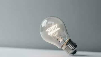 Glowing glass light bulb on grey background photo