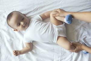 Baby massage. Mom doing gymnastics with kid. Mommy massaging cute baby boy. Moving baby's legs to help relieve constipation. Young mother doing exercises and movements to stimulate baby's bowels. photo