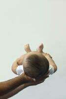 Dad holding 6-month-old baby boy against the white background. Father picking up his baby. Copy space. Family concept photo