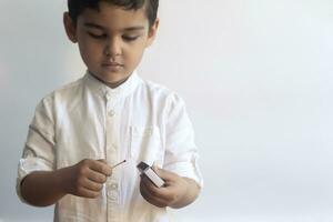 5-6 years old boy playing with fire. Middle eastern kid exploring fire. First tries of a child to play with match sticks photo