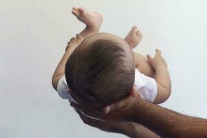 Dad holding 6-month-old baby boy against the white background. Father picking up his baby. Copy space. Family concept photo