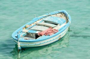 a small blue boat floating in the clear water photo