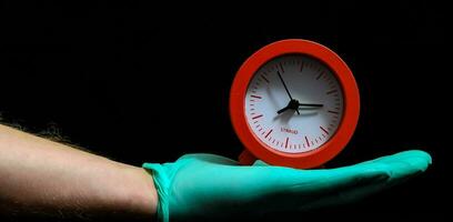 a person in a green glove holding a red clock photo