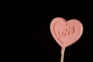 a pink heart shaped lollipop with the word love written on it photo