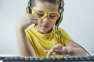 Homeschooling. Cute schoolboy in yellow learning foreign language online photo