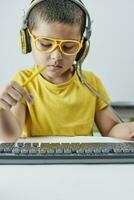 Homeschooling. Cute schoolboy in yellow learning foreign language online photo