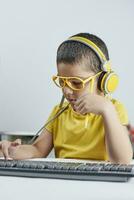 Homeschooling. Cute schoolboy in yellow learning foreign language online photo