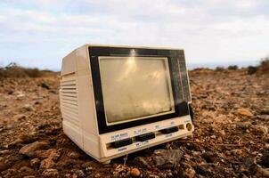 an old television sits on the ground in a field photo