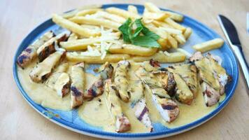 Ready to eat sliced chicken with cream sauce with french fries on a plate . video