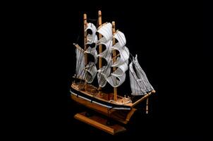 a wooden model of a sailing ship on a black background photo