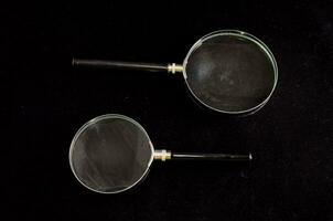 two magnifying glasses on a black surface photo