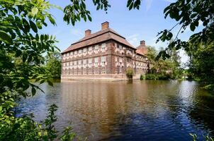 un grande ladrillo edificio se sienta en el borde de un lago foto