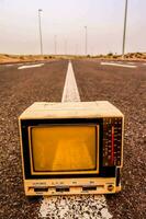 an old television sits on the side of a road photo