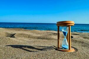 un reloj de arena con azul arena en el playa foto