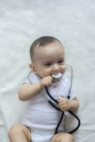 Little cute baby doctor. 6-month old baby boy playing with stethoscope. Kid having fun like a doctor photo